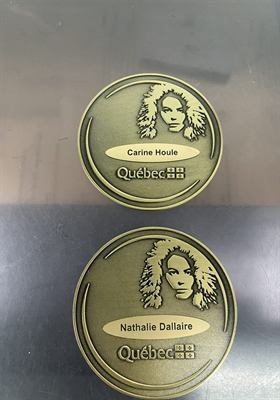 Deux médaillons de bronze gravés d’un visage stylisé et d’une plaquette nominative