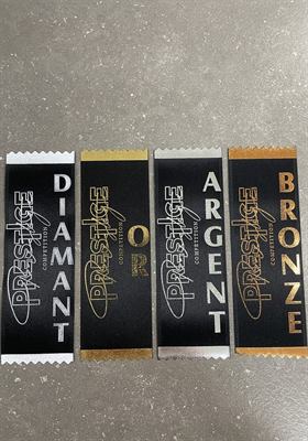 Quatre rubans de satin noir imprimés en diamant, or, argent et bronze, à bordure dentelée assortie et logo d’une compétition