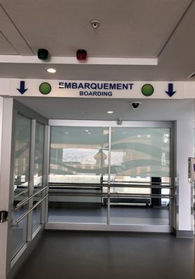 Enseigne « Embarquement / Boarding » installée à bord d’un traversier, avec film décoratif appliqué sur la cloison vitrée
