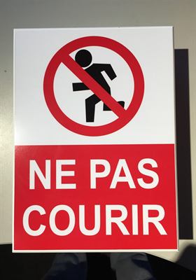 Panneau rouge et blanc à pictogramme barré et mention « Ne pas courir »
