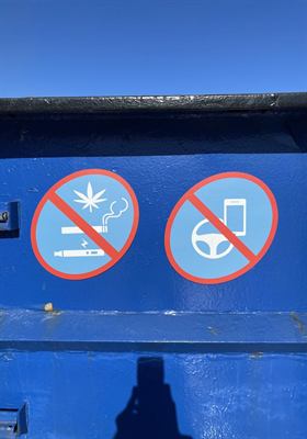 Deux pictogrammes ronds d’interdiction appliqués sur la coque bleue d’un navire, contre un ciel dégagé