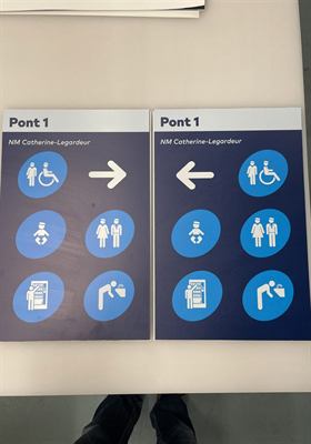 Deux panneaux d’orientation bleus « Pont 1 » à pictogrammes de services et flèches directionnelles opposées