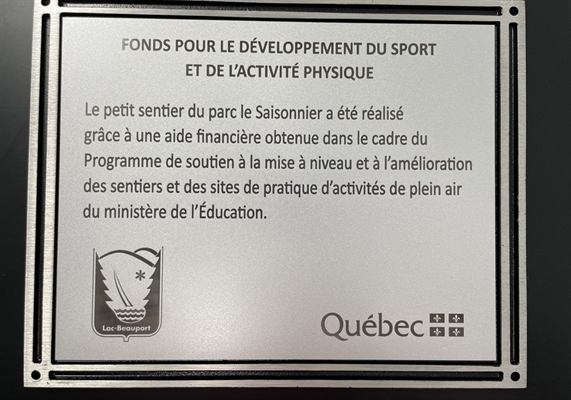 Plaque d’aluminium gravée soulignant une aide financière gouvernementale pour l’aménagement d’un sentier