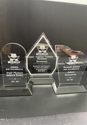 Trois trophées d’acrylique transparent aux découpes différentes, gravés du logo d’un programme sportif scolaire