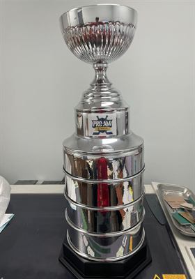 Réplique de grande coupe de hockey chromée sur socle noir, marquée du logo d’un tournoi