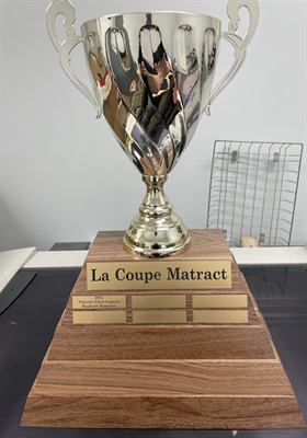 Grande coupe argentée à anses montée sur un socle de noyer à gradins garni de plaquettes annuelles